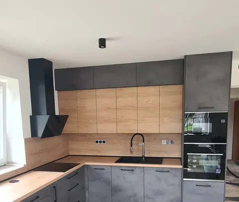Kuchyňská linka do L, spodní skříňky v betonovém dekoru, horní v dubu, dubová pracovní deska, černá digestoř a černý dřez