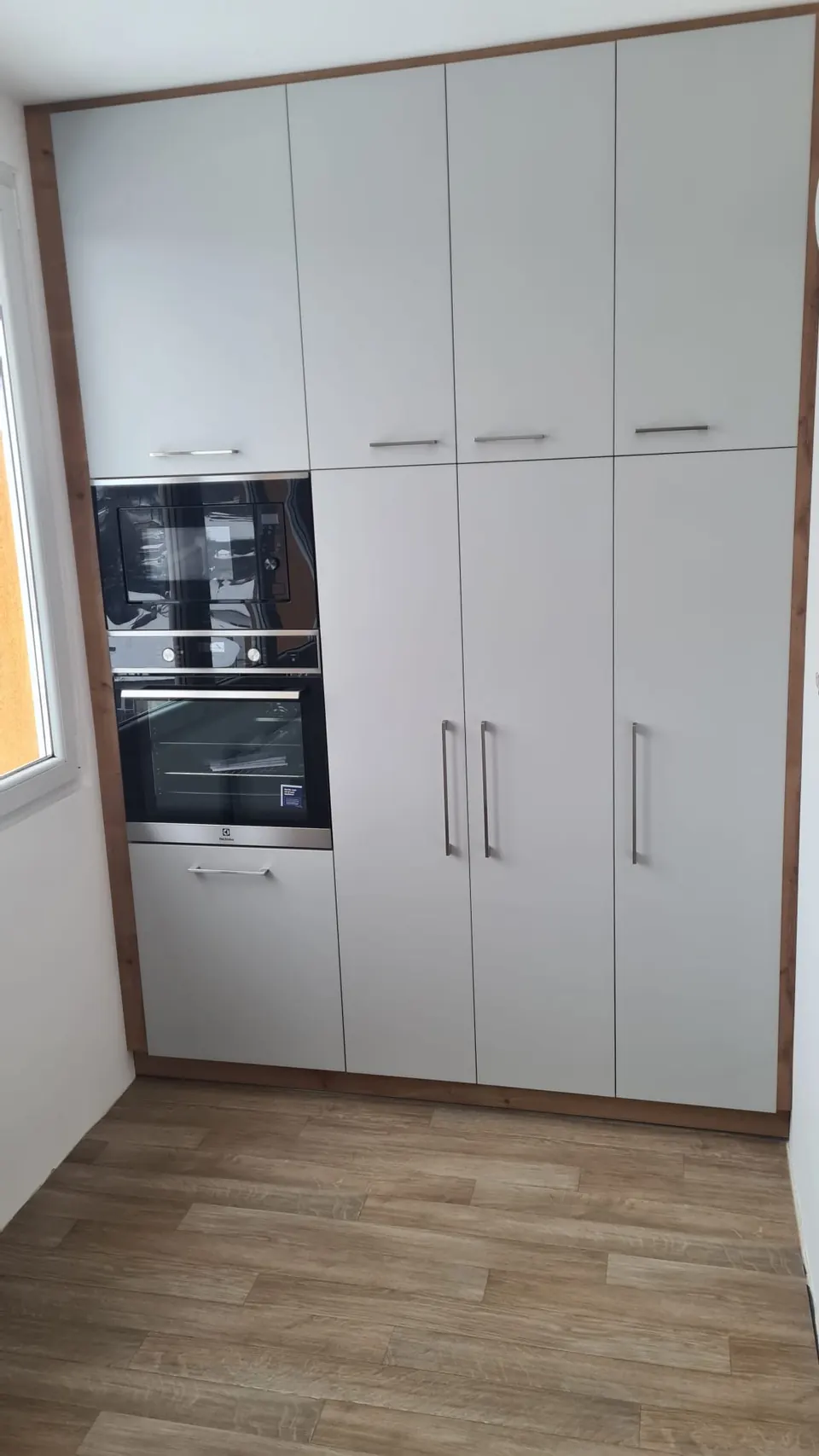 Vysoká kuchyňská sestava s vestavěnou troubou a mikrovlnnou troubou, světle šedá matná dvířka v dubovém rámu
